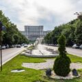 Palatul Parlamentului din București văzut de pe Bulevardul Unirii, cu fântâni arteziene și copaci pe ambele părți ale bulevardului